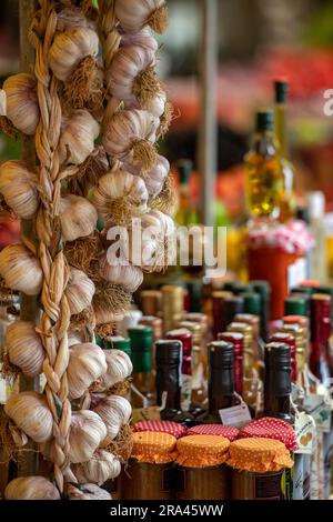 gousses d'ail, plaques d'ail, bulbes d'ail accrochés sur un étal de marché à trogir vendant des produits frais. bouteilles d'huile d'olive et de produits à l'ail Banque D'Images