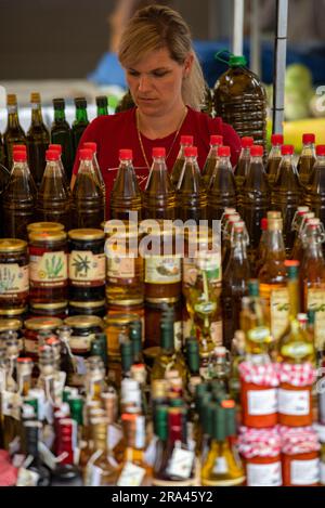 stallholder dans un marché vendant des pots d'huile d'olive et de miel à trogir, split, croatie. Banque D'Images