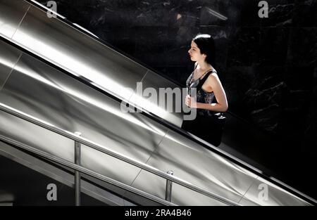 Belgrade, Serbie - 15 juin 2022: Une jeune femme se lève sur l'escalier roulant du métro, par une journée ensoleillée Banque D'Images