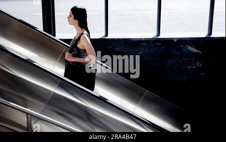 Belgrade, Serbie - 15 juin 2022: Une jeune femme se lève sur l'escalier roulant du métro, par une journée ensoleillée Banque D'Images