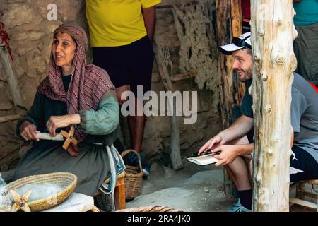 Le réacteur Hannah The Weaver démontre son métier pendant qu'un touriste écoute au Musée en plein air du village de Nazareth, en Israël. Banque D'Images