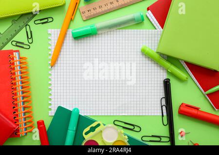Cadre composé de différents articles de papeterie avec bloc-notes vierge sur fond vert Banque D'Images