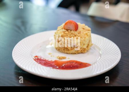 Gâteau Napoléon, préparé avec des couches de pâte feuilletée, de la crème fouettée et de la chapelure avec fraise sur le dessus et de la sauce servie sur l'assiette Banque D'Images