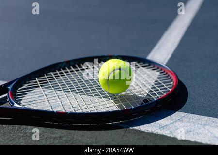 Gros plan de balle de tennis et raquette de tennis couché sur le court de tennis par jour ensoleillé, espace de copie Banque D'Images