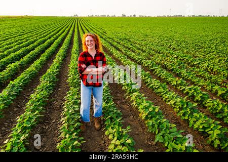 Portrait d'une agricultrice qui cultive du soja. Elle est satisfaite de la bonne progression des plantes. Occupation agricole. Banque D'Images