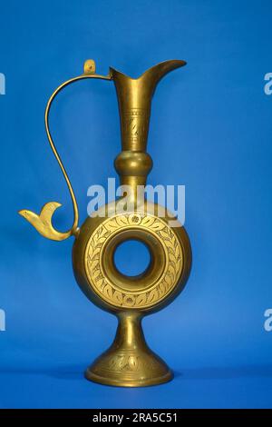 vase antique en laiton isolé dans fond bleu , utilisé traditionnellement comme verre de vin dans l'ancien arabe Banque D'Images