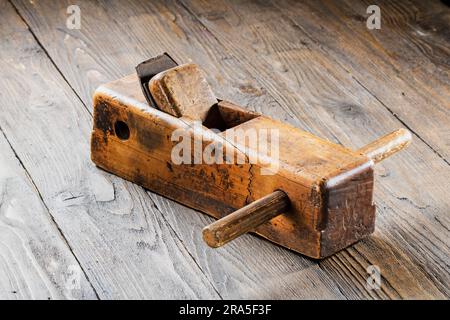Vieux rabot avec des signes d'usure et d'âge sur un fond en bois foncé. Banque D'Images