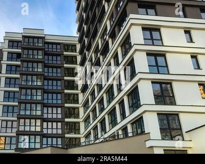 un bâtiment de plusieurs étages avec de nombreuses fenêtres se dresse dans la ville. décoration marron et blanche. cadres noirs dans les fenêtres, vitrage panoramique. desi élégant Banque D'Images