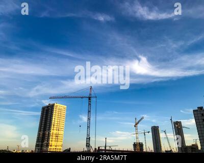 les grues de construction érigent de nouvelles maisons à partir de blocs. nouvelles constructions, lieux de vie des gens. dans les maisons vitrage panoramique, différentes couleurs de Banque D'Images