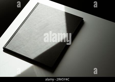 Maquette de couverture de magasin vierge noire, modèle à l'angle de la table avec lumière naturelle et ombre Banque D'Images