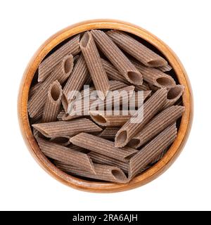 Penne de sarrasin, pâtes de grains entiers sans gluten, dans un bol en bois. Nouilles brun foncé, faites de semoule de sarrasin pur, extrudées en forme de cylindre. Banque D'Images