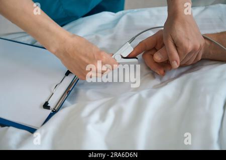 Médecin mettant l'oxymètre de pouls sur le doigt du patient mâle dans la clinique Banque D'Images