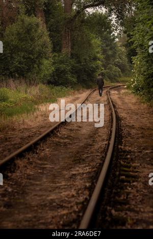Un homme sans abri fatigué marche sur les rails Banque D'Images