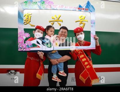 (230701) -- XINING, 1 juillet 2023 (Xinhua) -- les préposés posent pour une photo avec des passagers devant un train à grande vitesse sur la section Xining-Golmud du chemin de fer Qinghai-Tibet à Xining, dans la province de Qinghai, au nord-ouest de la Chine, à 1 juillet 2023. Samedi, les trains à grande vitesse Fuxing ont officiellement commencé à fonctionner dans la section Xining-Golmud du chemin de fer Qinghai-Tibet. Avec une longueur totale d'exploitation de 829 km, il part de Xining, capitale de la province de Qinghai, dans le nord-ouest de la Chine, à l'est et passe par Huangyuan, Haiyan, Ulan, Delingha à la gare de Golmud à l'ouest, selon C Banque D'Images