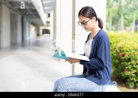 Femme intelligente assise lisant un livre utiliser le temps libre pour l'apprentissage de l'éducation bookworm nerd à l'université. Banque D'Images