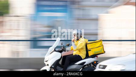 Belgrade, Serbie - 20 mai 2023: Personne de livraison de service de messagerie travaillant pour Glovo à cheval avec un conteneur arrière dans la circulation urbaine Banque D'Images