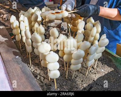 Le commerçant gril sur le charbon traditionnel japonais brochettes de farine de riz, confections de wagashi appelé kushi-dango si sur brochette ou sumibi-y Banque D'Images