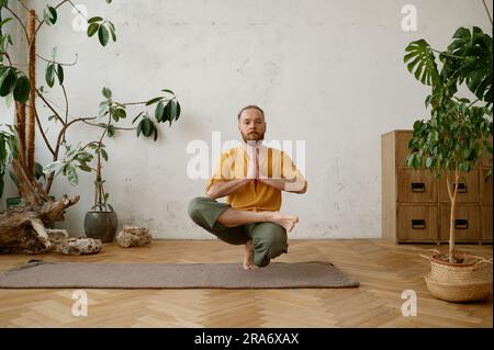 Homme à la coupe forte qui s'équilibre sur une jambe en position de squat Banque D'Images