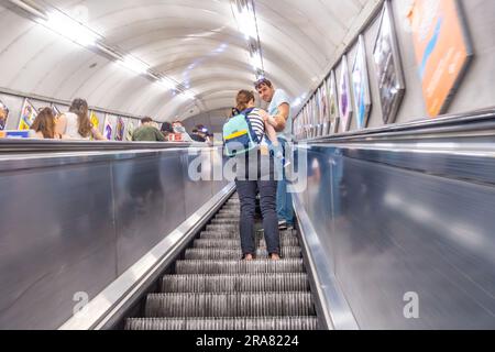 Monter un escalier mécanique dans une station de métro de Londres. Banque D'Images