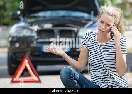 une femme appelle le service d'urgence parce que sa voiture s'est effondrée Banque D'Images