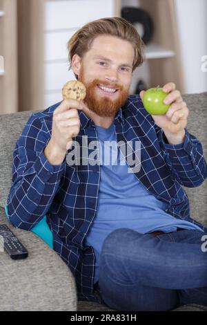 homme ayant un choix difficile entre une alimentation saine et malsaine Banque D'Images