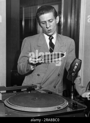 New York, New York: c. 1947 disque NBC le jockey Wayne Howell joue des enregistrements de stars sur le programme du samedi soir, 'Musical Merry-Go-Round'. Le programme a été un premier effort pour faire des vidéos de musique. Banque D'Images