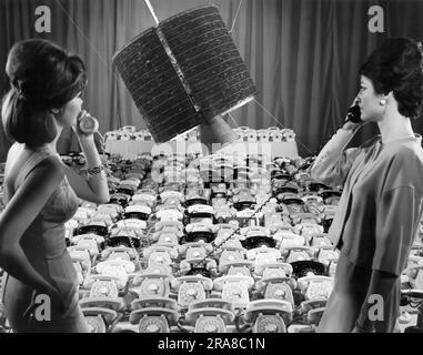 Los Angeles, Californie : avril 1965 les employés de Hughes Aircraft Company utilisent deux des 480 téléphones que le satellite de communication « Early Bird » d'Intelsat 1 peut transmettre dans des conversations téléphoniques bidirectionnelles entre l'Europe et l'Amérique du Nord. Banque D'Images