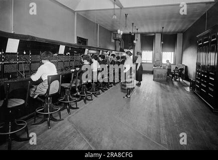États-Unis, c. 1915 Un standard téléphonique avec des opérateurs reliant les appels et deux superviseurs à l'arrière et les supervisant. Banque D'Images