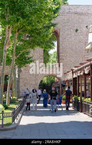 Des gens, y compris une femme musulmane marchant dans une rue à côté de l'aqueduc de Valens, un aqueduc romain à Istanbul, Turquie Banque D'Images