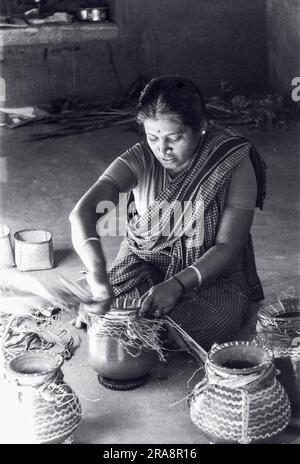 Photo en noir et blanc, Une femme qui lie le groupe de curcuma à l'ustensile Pongal, Tamil Nadu, Inde, Asie. Photographié en 1970 Banque D'Images