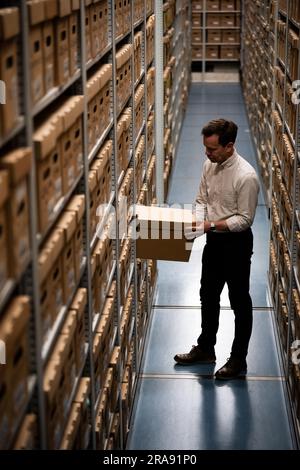 Laurence Ward, responsable des services numériques pour les Archives métropolitaines de Londres (LMA), retire une boîte de l'installation de stockage des plus grandes archives historiques du Royaume-Uni. Avec plus de 100km livres, cartes, photographies, films et documents datant de 1067 détenus dans des salles fortes, le LMA est le principal dépôt d'archives du gouvernement local pour la région du Grand Londres, y compris la City de Londres et est le plus grand bureau de disques du comté au Royaume-Uni. Date de la photo: Mardi 27 juin 2023. Banque D'Images