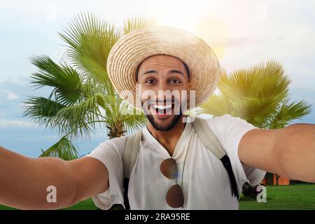 Jeune homme souriant en chapeau de paille emportant un selfie à la station Banque D'Images