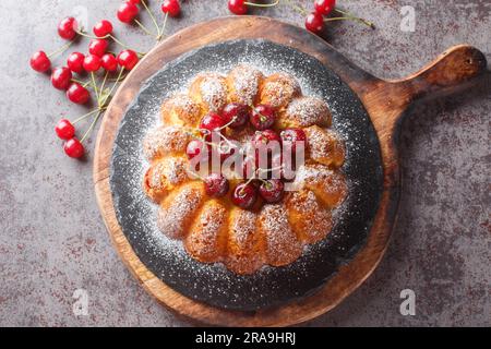 Délicieux biscuit vanille cerise petit gâteau décoré de baies fraîches et de sucre en poudre sur une planche en bois sur la table. Haut horizontal vi Banque D'Images