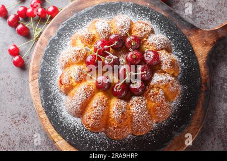 Gâteau à la vanille maison arrosé de sucre en poudre sur une planche en bois sur la table. Vue horizontale du dessus Banque D'Images