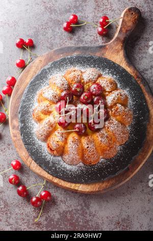 Gâteau de cerise fraîchement cuit en gros plan sur une planche de bois sur la table. Vue verticale du dessus Banque D'Images