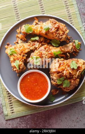 Poulet frit thaï du sud avec échalotes croustillantes et sauce Chili douce en gros plan sur une assiette sur la table. Vue verticale du dessus Banque D'Images