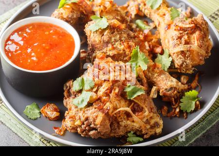 Poulet frit thaïlandais croustillant et juteux mariné avec de la coriandre, de l'ail et des assaisonnements asiatiques sur une assiette sur la table. Horizontale Banque D'Images