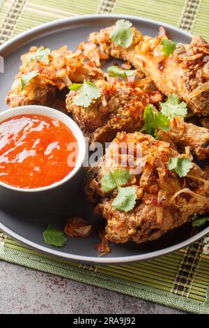 Hachez le poulet frit thaï de style Yai avec un oignon croustillant en gros plan sur une assiette sur la table. Verticale Banque D'Images