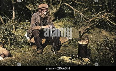 Un tramp assis à côté du feu qu'il a fait. Un pot est en train de bouillir dessus. Date : C. 1920s Banque D'Images