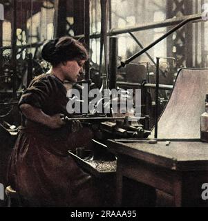 Femme française assise à son banc, dans une usine française, usinant des épinglettes de percuteur en laiton pour des obus d'artillerie. Date: 1916 Banque D'Images