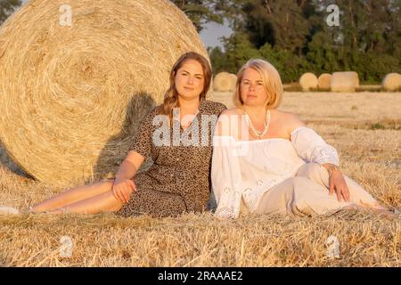 Mère et fille assises en été sur le terrain. Mère heureuse et sa petite fille dans le champ de tournesol. Banque D'Images
