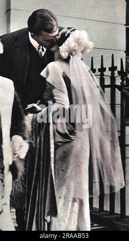 Mme Charles Sweeny, ancienne Mlle Margaret Whigham et plus tard la duchesse d'Argyll (1912-1993) photographiée embrassant son mari Charles Sweeny Au revoir avant d'être présentée sur son mariage à la troisième Cour de la saison de Londres. Margaret avait déjà été présentée comme un desbutante en 1930 mais les femmes de la société étaient généralement présentées une fois de plus après le mariage. Comme M. Sweeny, golfeur professionnel, était américain, elle a été présentée par Mme Bingham, épouse de l'ambassadeur américain. Date: 1934 Banque D'Images