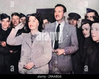 Mme Ronald Tree et l'acteur David Niven à un concours de fléchettes dans une cantine. Nancy Lancaster (1897 - 1994), née Perkins, était une femme influente de cuisine américaine, décoratrice d'intérieur et designer de jardin. Elle épousa Ronald Tree en 1920, déménaga en Grande-Bretagne en 1927; le couple divorça en 1947 et elle épousa Claude Lancaster en 1948. Elle a été associée au style de maison de pays anglais. Date: 1939 Banque D'Images