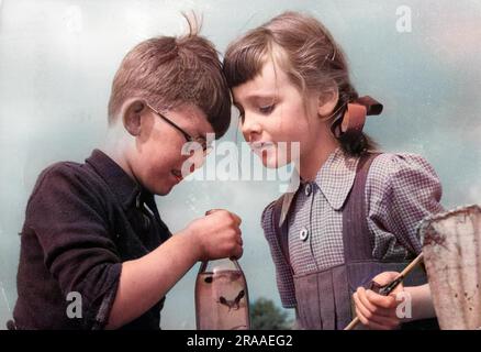 Un petit garçon et une petite fille se mettent à la bouteille de lait des tiddlers qu'ils viennent de mettre en filet ! Date: 1950s Banque D'Images