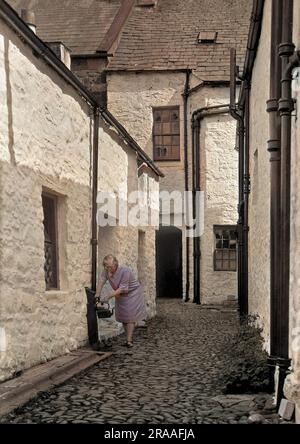 Une femme remplissant une bouilloire depuis un robinet extérieur à Newhaven, dans l'est du Sussex. Date: 1920s Banque D'Images