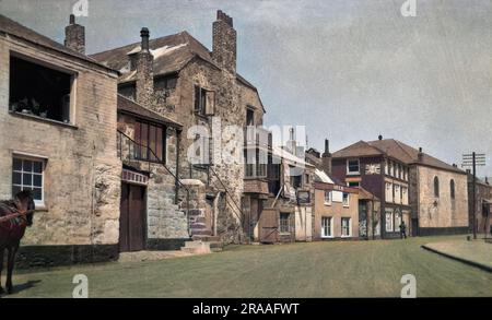 Une scène de rue à St Ives, en Cornouailles, avec des maisons et des boutiques, et un panneau publicitaire BP. Date: 1922 Banque D'Images