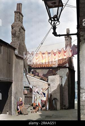 Une scène de rue d'Édimbourg, montrant une femme âgée assise au soleil près d'une ligne de lavage. Banque D'Images