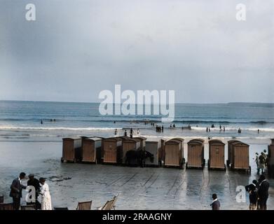 Cabines de baignade avec roues sur la plage à Newquay, Cornwall, avec quelques vacanciers. Date: 1925 Banque D'Images