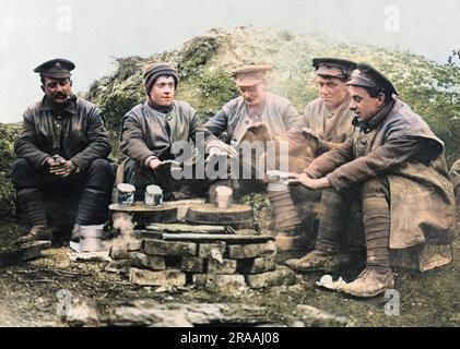 Les soldats britanniques gardent la chaleur autour d'un four sur le front occidental pendant la première Guerre mondiale. Les boîtes de nourriture sont en train d'être réchauffées prêtes pour leur repas. Date: Vers 1916 Banque D'Images