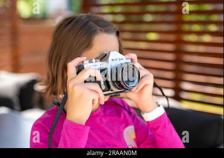 Calgary, Alberta - 1 juillet 2023 : jeune fille tenant un appareil photo reflex Ricoh d'époque. Banque D'Images